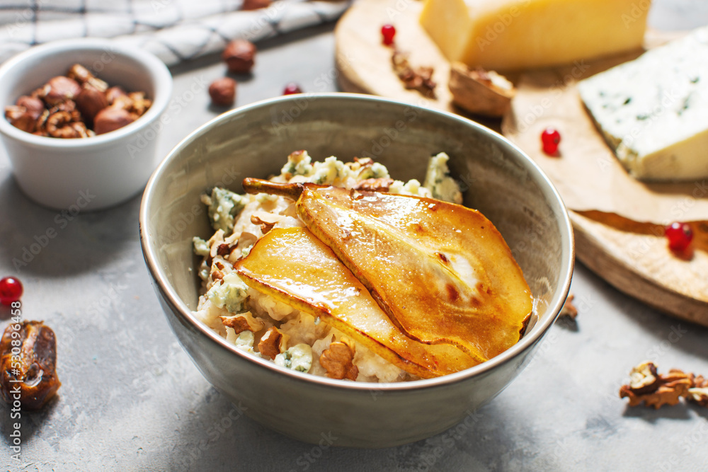 Pear and gorgonzola oatmeal with walnuts on concrete table Pear and gorgonzola oatmeal with walnuts on concrete table