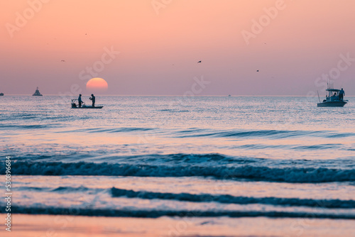 Fishermen on their boat as the sun rises above them in the Atlantic ocean