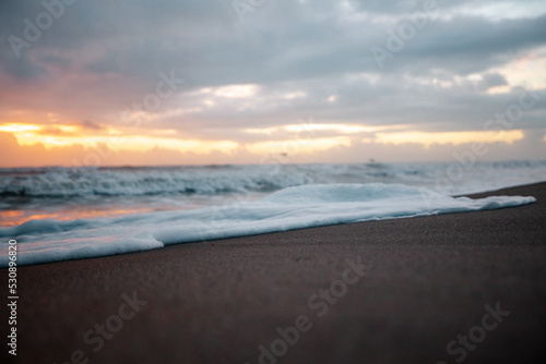 Foamy waves coming in during sunrise at the beach. 