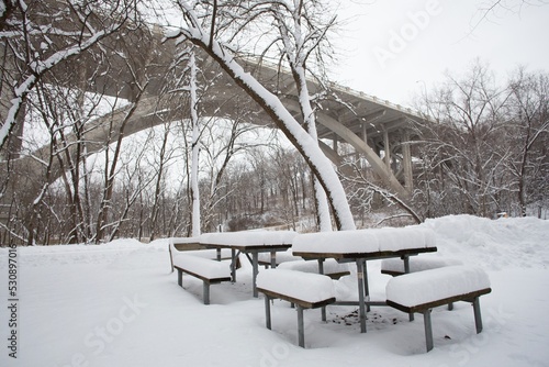 Picnic tables covered in snow, at Fort Snelling State Park in St. Paul, Minnesota, in winter.  photo