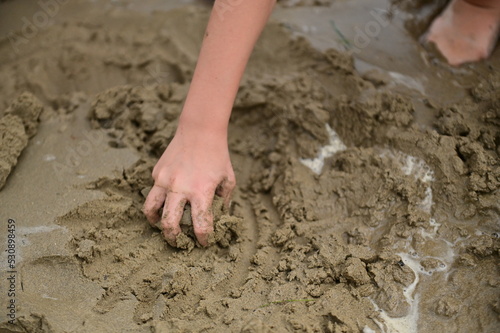 Child is playing in the beach, game with sand and hands, detail of the hands