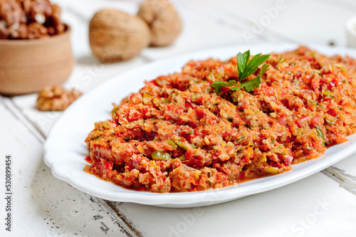Hot pepper adjika on a plate on a white wooden background. Georgian cuisine.