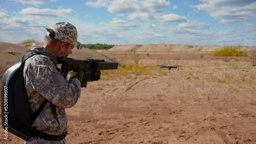 military man uses an anti drone weapon to land an aerial quadcopter back view