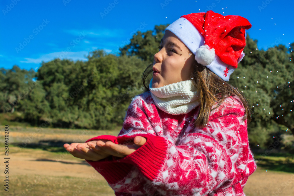 Obraz premium Adorable little girl enjoying Christmas, wearing Christmas clothes and earmuffs. Image with copy space