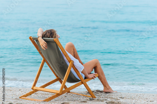 Girl sitting on a sun lounger by the sea