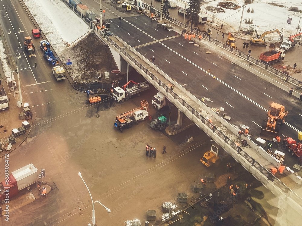construction of a new bridge in the city center, view from above. construction machinery is working on laying new asphalt. marking and pavement