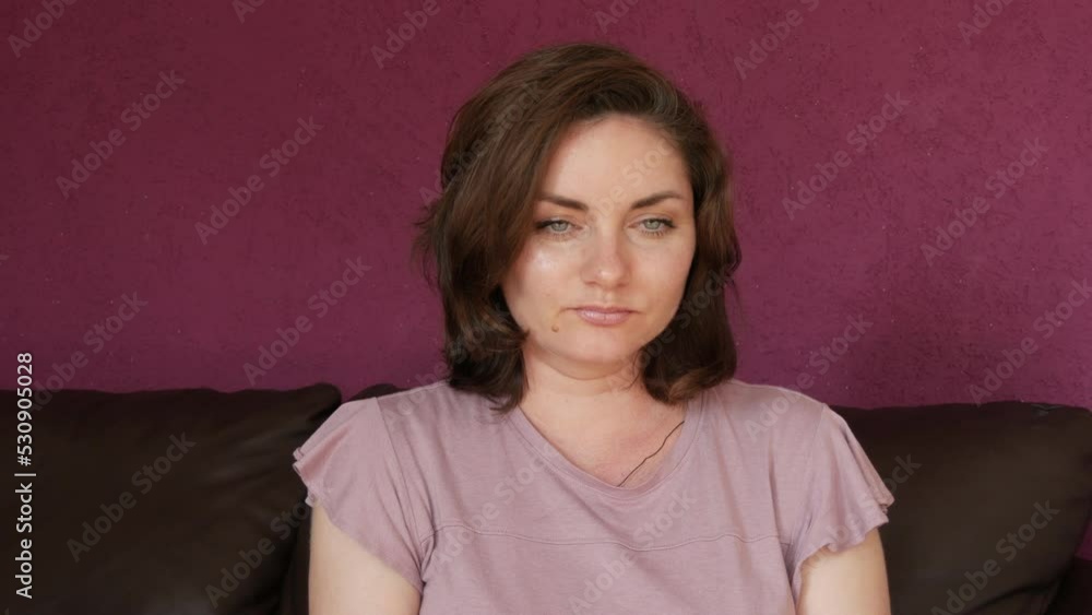Close-up portrait of a young beautiful woman with green eyes and dark hair, who looks directly into the camera Seriously and slyly looking at the camera on a leather sofa in the room Close-up portrait of a young beautiful woman with green eyes and dark hair, who looks directly into the camera Seriously and slyly looking at the camera on a leather sofa in the room