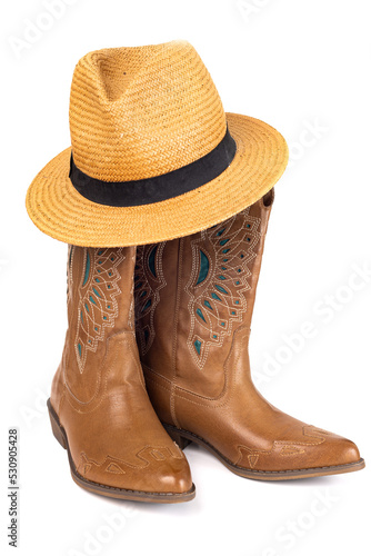 Leather cowgirl boots with embroidery and straw hat isolated on white background.