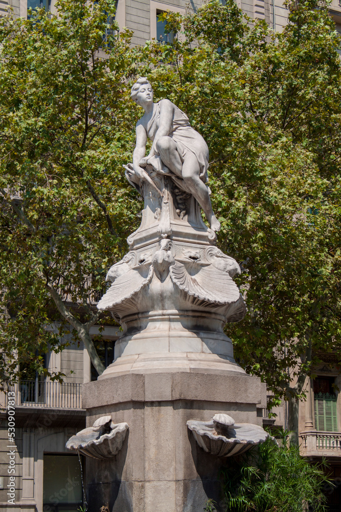 An exterior view of the historical Diana Fountain stands in the central section of Barcelona's Gran Via in Catalonia, Spain, Europe. Tall marble statue of the Roman goddess Diana the huntress.