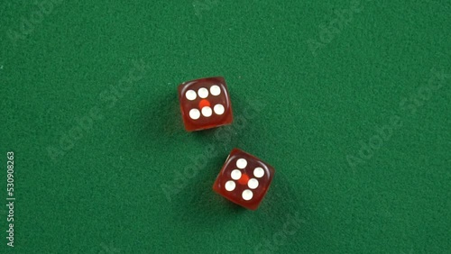 Two red roll dices and stops on the table with double 6 in slow motion.