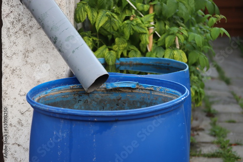 Blue rain barrels to collect rainwater that flows from roof gutters