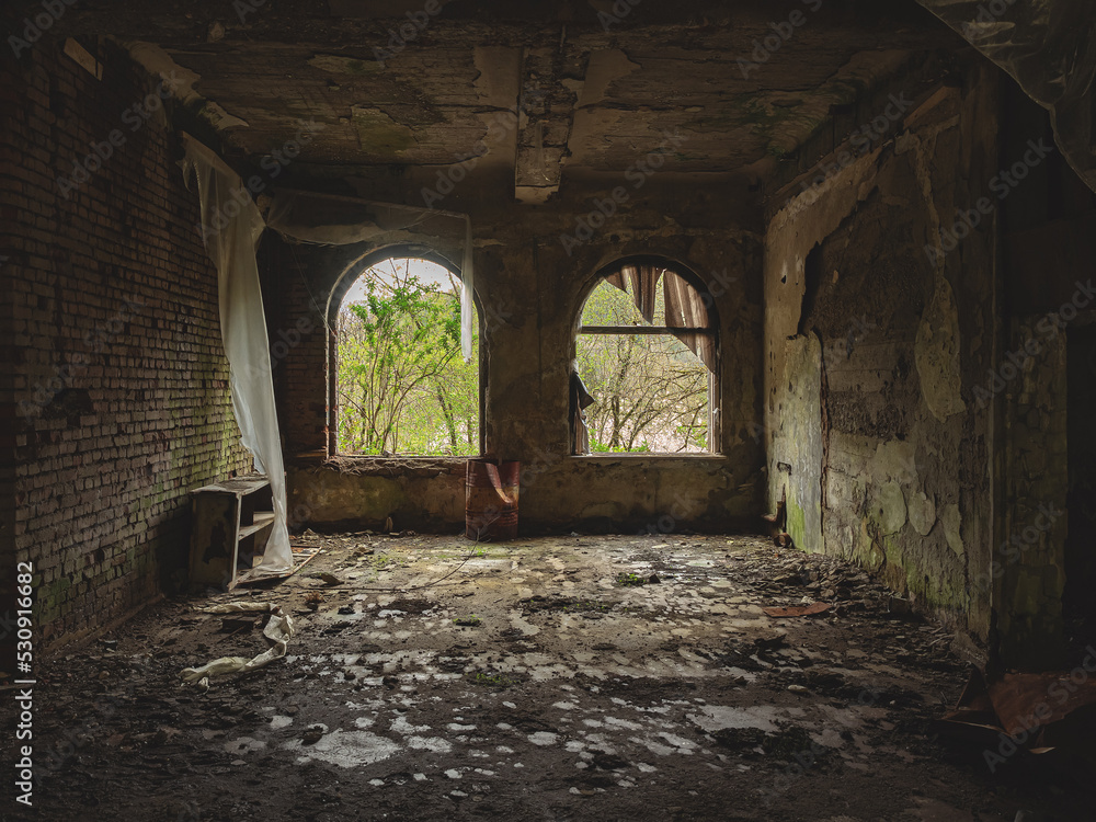 Arched windows in a dark decaying abandoned old room. Crumbling wall inside a dark abandoned room. Walk through the old ruins. Ghost town. War torn place
