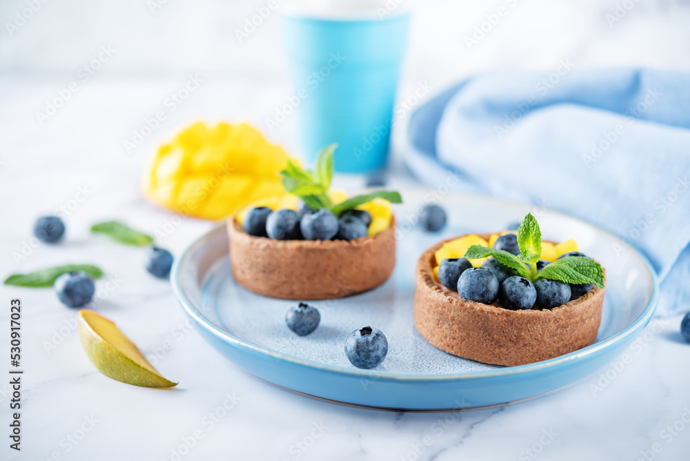 Chocolate tartlets with chocolate cream filling and mango fruit with blueberries Chocolate tartlets with chocolate cream filling and mango fruit with blueberries