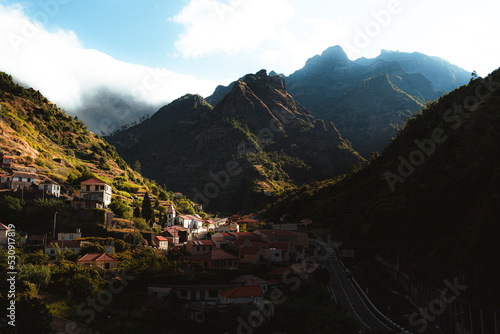 Panoramic scenery of the sun illuminates half the village through the mountains of Madeira island.