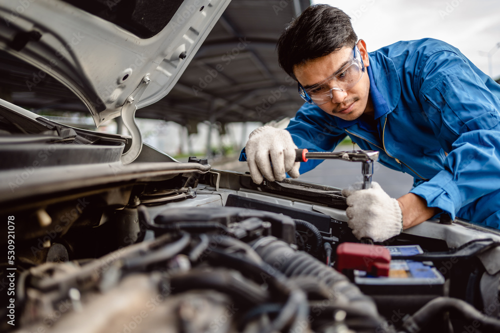Auto mechanic repairman using a socket wrench working engine repair in the garage, change spare part, check the mileage of the car, checking and maintenance service concept. Auto mechanic repairman using a socket wrench working engine repair in the garage, change spare part, check the mileage of the car, checking and maintenance service concept.
