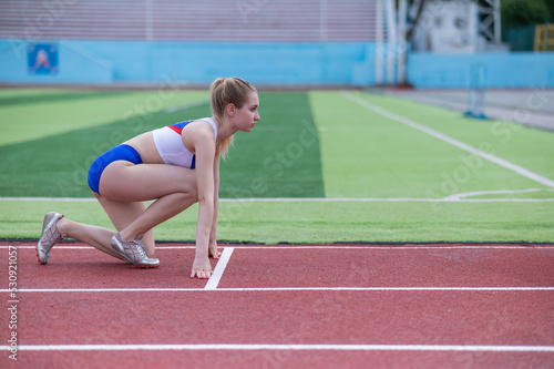 Female runner in the stadium is ready to race.