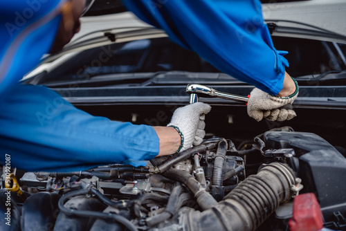 Close up of view Auto mechanic repairman using a socket wrench working engine repair in the garage, change spare part, check the mileage of the car, checking and maintenance service concept.