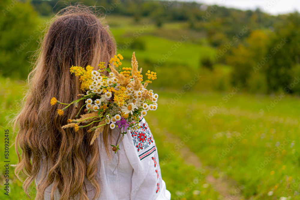 Naklejka premium Girl with flower bouqet in a green field