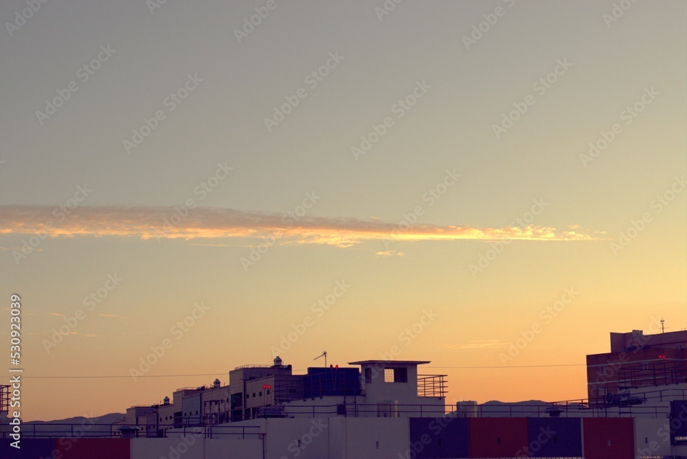 Naklejka premium Dawn, sunrise illuminates a funny cloud and the roofs of urban new buildings, a banner, a screensaver.
