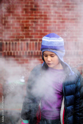 A beautiful serious child standing in smoke gazes down photo