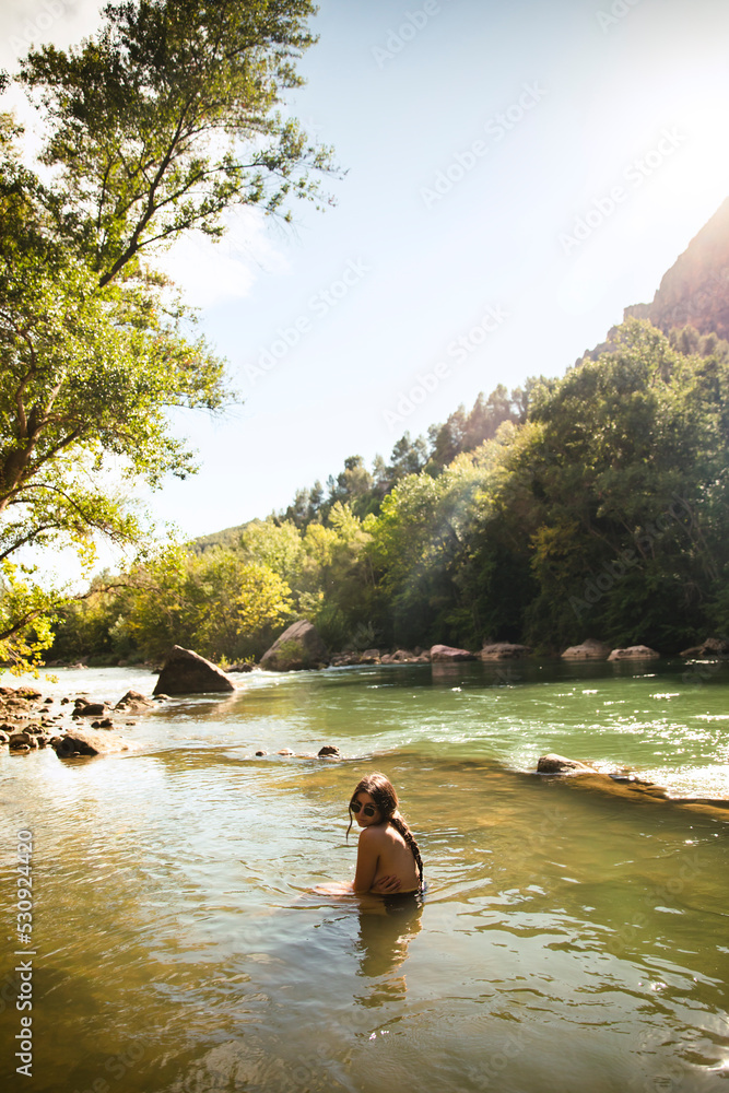 Naked girl bathing in a river surrounded by trees during sunset foto de Stock Adobe Stock