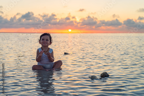 Latin baby boy enjoying the water with a beautiful sunset behind © Cavan