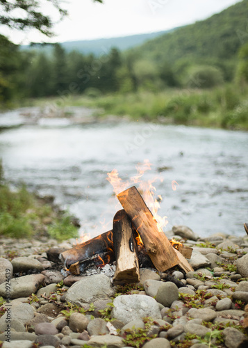 Campfire next to a river in the woods

 photo