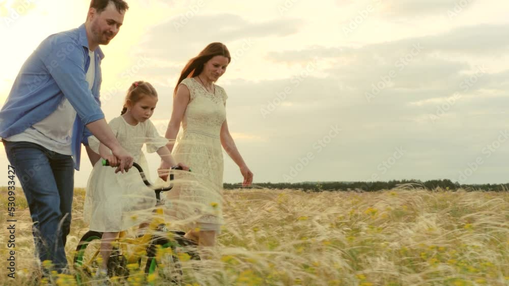 happy parents teach smiling child daughter ride bike. happy family