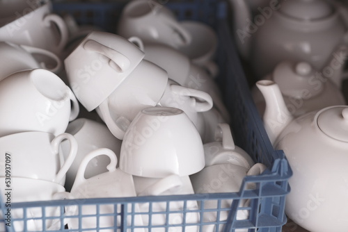 Pile of clean white cups in plastic box. Close up.