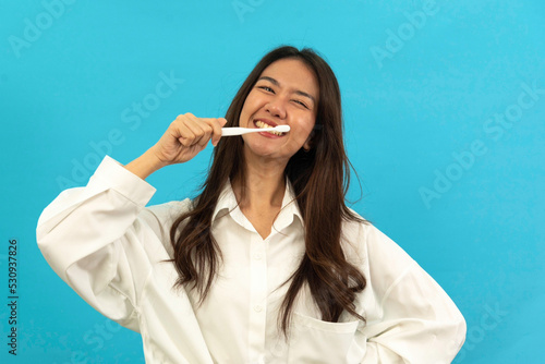 woman holding toothbrush with toothpaste smiling happy and positive on blue background. Dentistry conceptual photo photo
