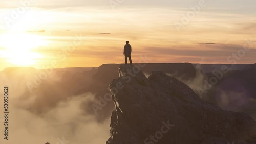 Epic Adventure Composite of Man Hiker on top of a rocky mountain. Dramatic Sunset Sky. 3d Rendering peak. Background landscape from North America. Freedom Concept. Animation