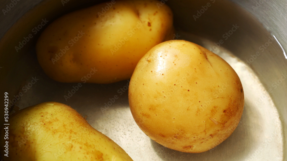 Close-up of golden yellow potatoes soaked in water in a pot. Close-up of golden yellow potatoes soaked in water in a pot.