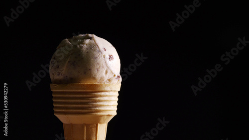 Close-up of Chocolate Chip ice cream on brown cone on black background.