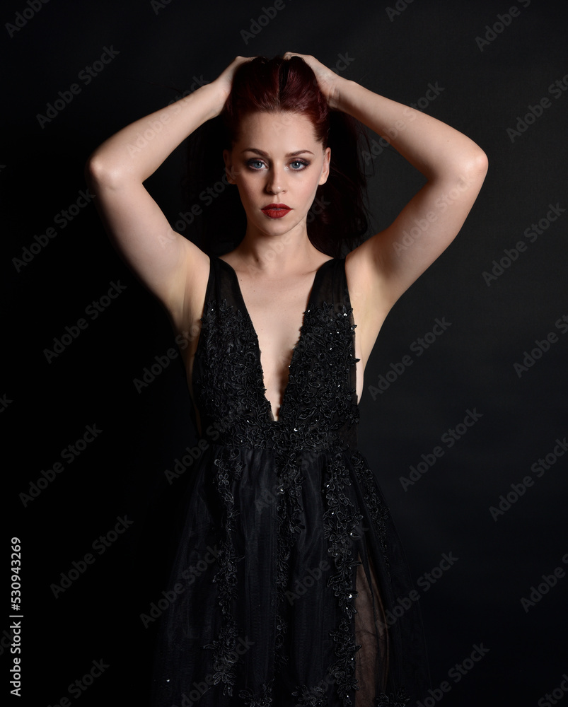 close up portrait of beautiful woman with red hair, wearing black dress with elegant gestural hand poses on a dark studio background with moody lighting. close up portrait of beautiful woman with red hair, wearing black dress with elegant gestural hand poses on a dark studio background with moody lighting.