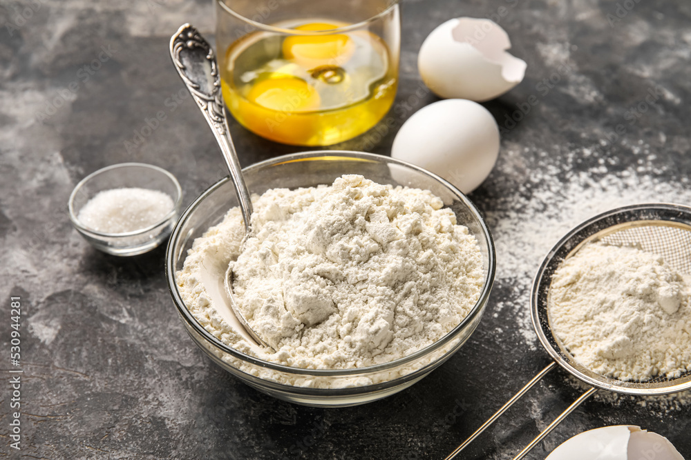 Bowl with flour and eggs on dark table, closeup