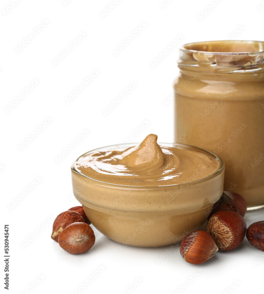 Bowl and jar of tasty hazelnut butter on white background, closeup Bowl and jar of tasty hazelnut butter on white background, closeup
