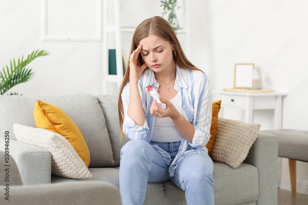 Young woman with nosebleed and tissue at home Young woman with nosebleed and tissue at home
