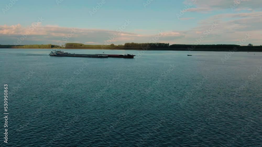 Flying towards a big transportation barge sailing on a big river right after sunset Flying towards a big transportation barge sailing on a big river right after sunset