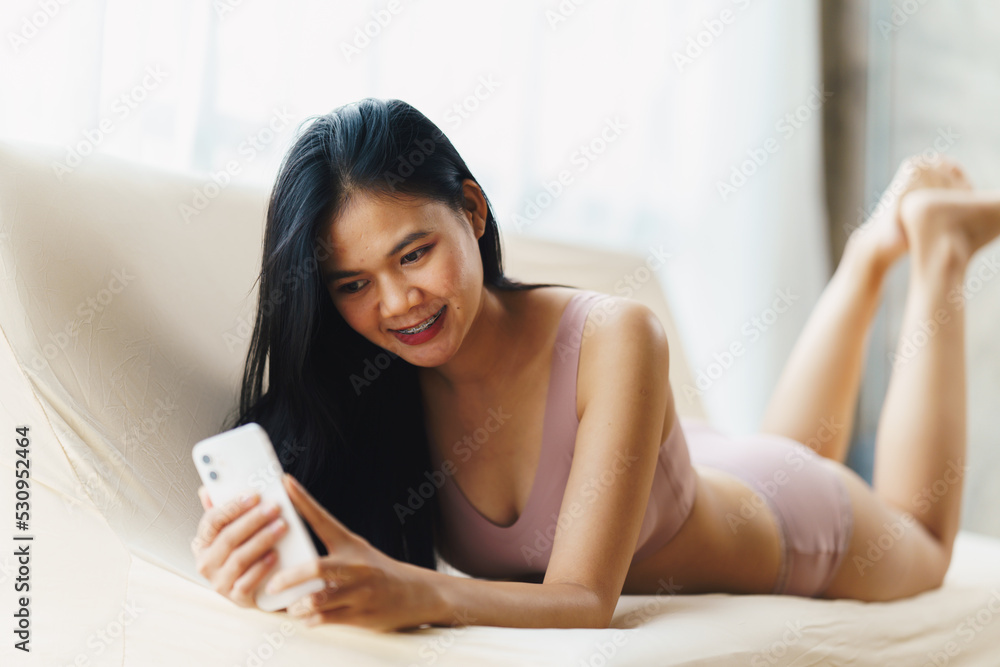Sexy asian woman using mobile phone on the sofa. Sexy asian woman using mobile phone on the sofa.