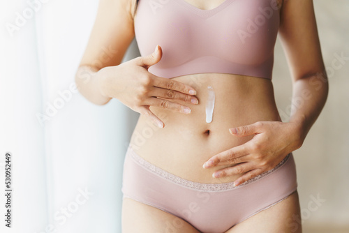 Girl puts cream on skin in abdomen. Skin Care Concept