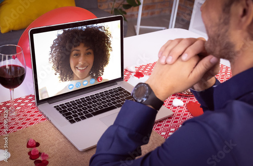 Diverse couple making valentines date video call the woman on laptop screen smiling