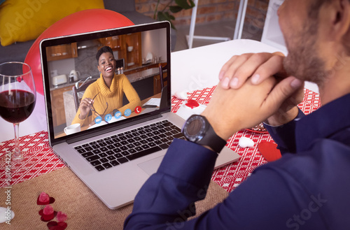 Diverse couple making valentines date video call the woman on laptop screen laughing