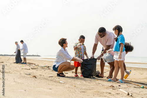 Group of Diversity family on summer holiday vacation. Parents teaching children kid picking up plastic bottle and garbage on the beach. Environment protection volunteer and waste pollution concept