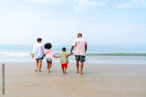 African family on beach holiday vacation. Father and mother with little daughter and son playing together on the beach at summer sunset. Parents with kid enjoy outdoor lifestyle together at the sea