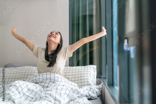 Wallpaper Mural Young beautiful Asian woman in pajama wake up in the morning with stretching her body. Attractive girl feeling fresh and happy while waking up for start a new day on the bed in bedroom. Torontodigital.ca