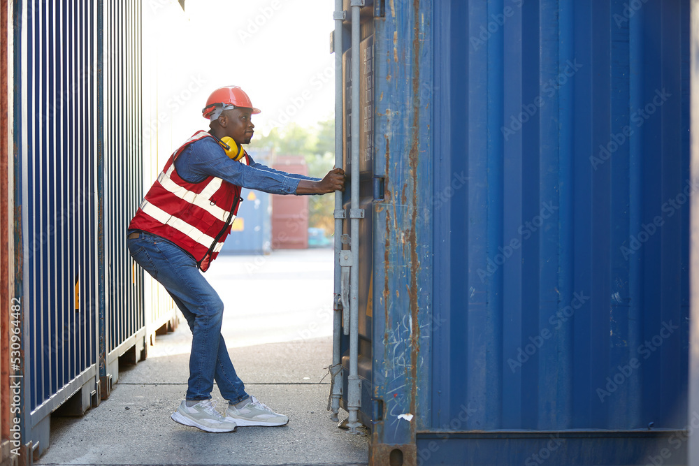 African factory worker or foreman opening the container door in warehouse storage African factory worker or foreman opening the container door in warehouse storage