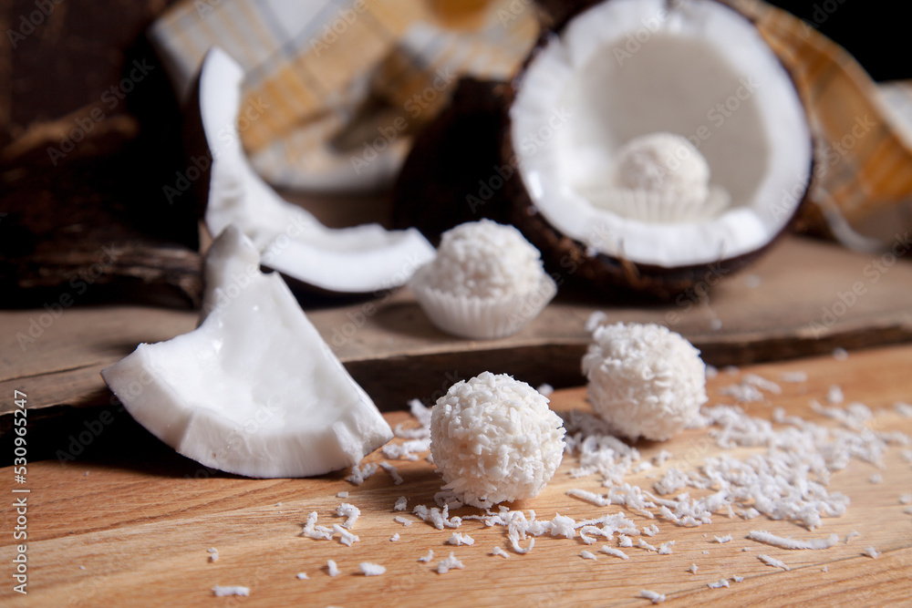 Close up of coconut with white pulp, coconut chip and white candies on wooden background.. Close up of coconut with white pulp, coconut chip and white candies on wooden background..