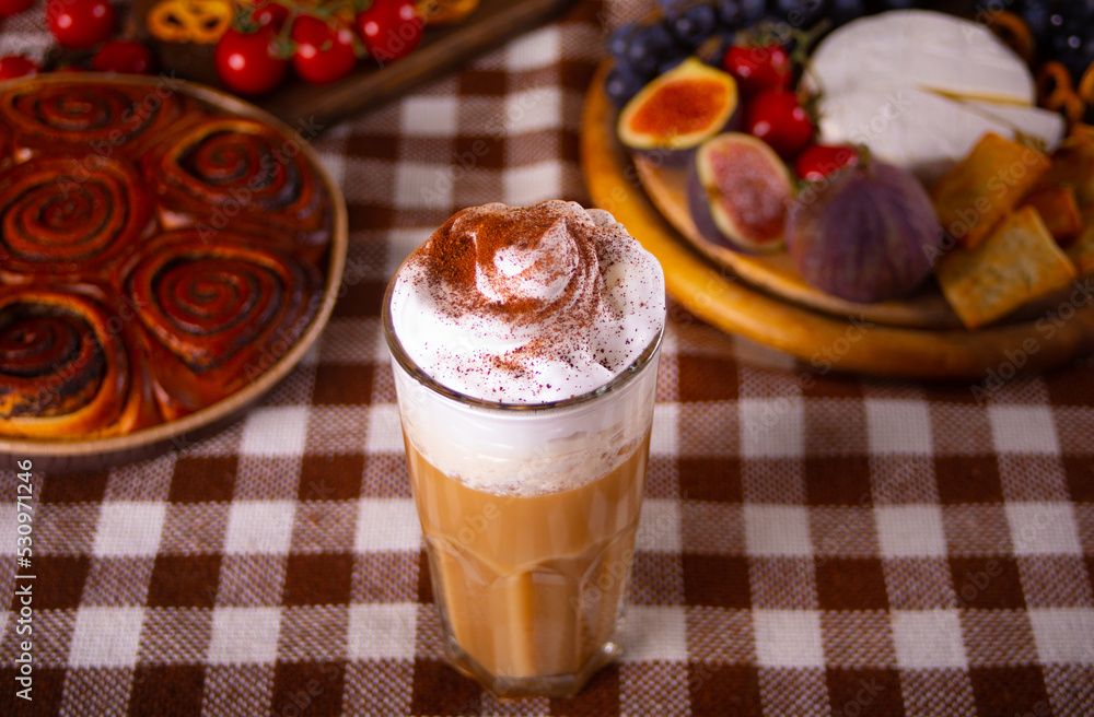 Pumpkin spice whipped latte in glass. Hot autumn drink beverage. Nearby delicious pie and appetizers fruits and cheese. Pumpkin spice whipped latte in glass. Hot autumn drink beverage. Nearby delicious pie and appetizers fruits and cheese.