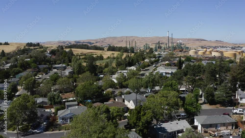 Aerial view of houses with a factory in the background - ascending, drone shot Aerial view of houses with a factory in the background - ascending, drone shot