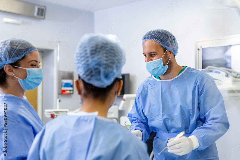 Medical team performing operation. Group of surgeon at work in operating theatre toned in blue. Doctor operation in operation room at hospital concept for insurance advertising. Medical team performing operation. Group of surgeon at work in operating theatre toned in blue. Doctor operation in operation room at hospital concept for insurance advertising.